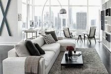 a contemporary living room with a creamy sectional sofa, a grey rug and textiles, printed pillows, a cool floor lamp and a sitting zone by the window