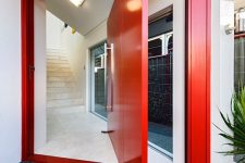 a fantastic red pivot door with a large handle is a gorgeous color statement and its design adds even more interest to the space
