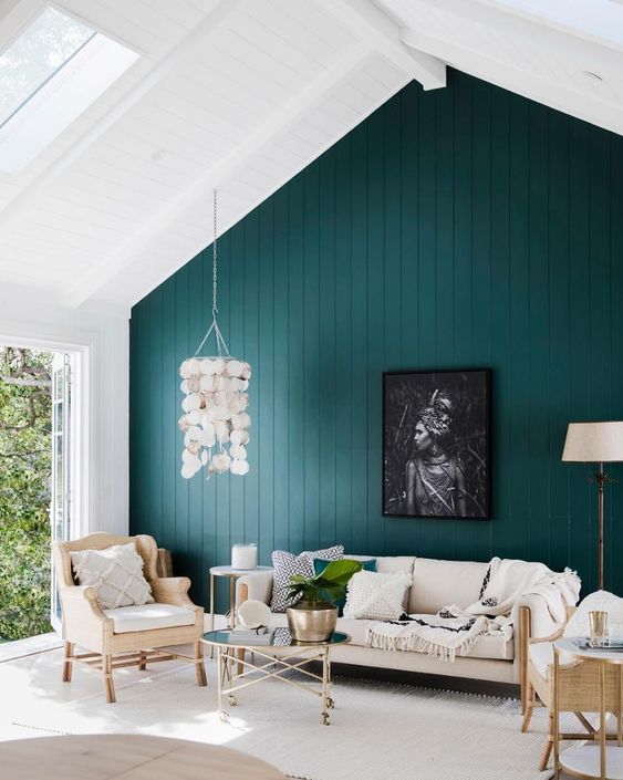 a lovely modern attic living room with a dark green accent wall, neutral funiture, a seashell pendant lamp and printed textiles