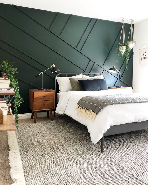 a mid-century modern bedroom with a dark green panelled accent wall, a metal bed, matching nightstands, open shelves and potted greenery