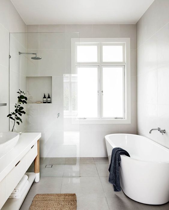 a neutral and lightweight bathroom with large scale tiles, an oval tub, a large vanity and dark touches for a fresh look