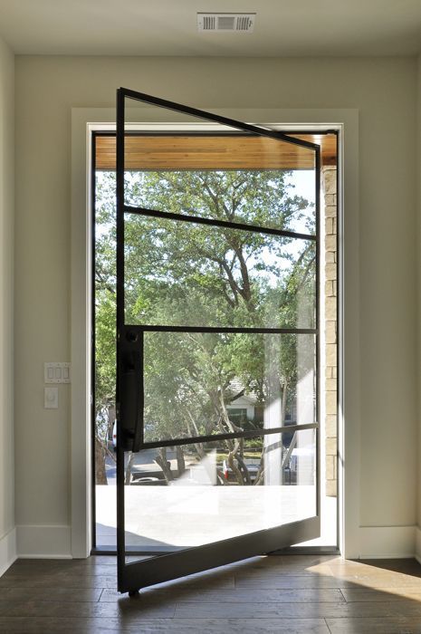 a pretty black metal frame and glass pivot entry door looks very chic and very lightweight and adds interest to the entrance