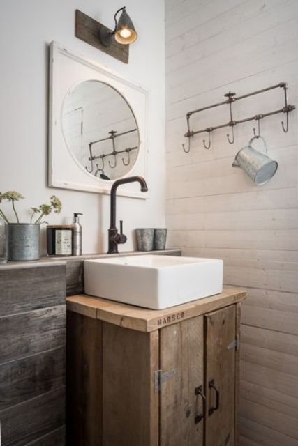 a rustic bathroom with white planked walls, reclaimed wood and a reclaimed wood vanity, dark metal fixtures and vintage touches