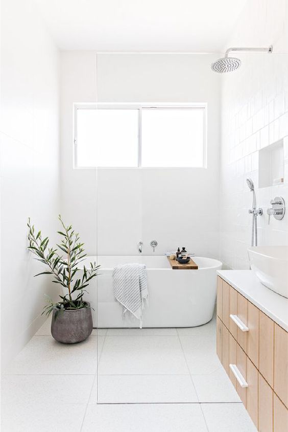 a serene bathroom in neutrals, with square large scale tiles, a wood floating vanity, a niche shelf and a potted plant