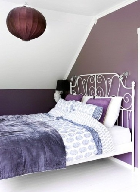a small attic bedroom with a white forged bed, a purple paper lamp over the bed and purple and white bedding is cozy