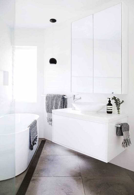 a small contemporary bathroom with a tub, a white floating vanity and a round sink, a large mirror and a shower