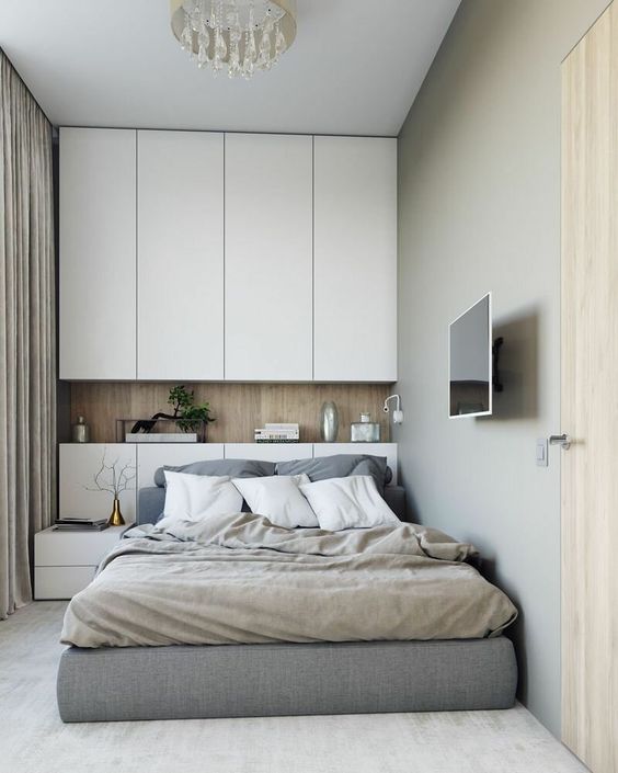 a small contemporary bedroom with sleek white storage units, an upholstered bed and a small nightstands, neutral bedding is chic