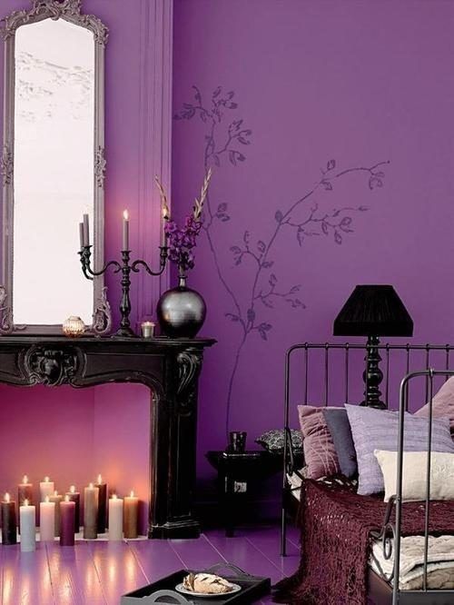 a sophisticated bedroom with a purple accent wall, a non-working fireplace with candles, a vintage metal bed with pillows and elegant decor