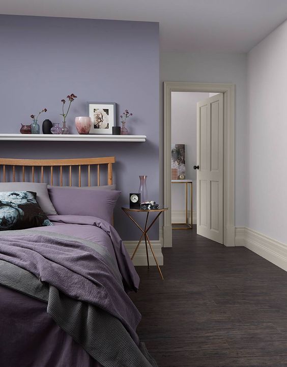 A Stylish Modern Bedroom With A Lilac Accent Wall A Wooden Bed With Lilac And Grey Bedding A Floating Shelf With Lovely Decor 