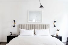 a stylish neutral bedroom with a grey upholstered bed, a wooden bench, dark matching nightstands and a black chandelier