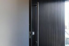 a super elegant black wooden slab door with a large metal handle is a cool and bold idea for a minimalist or conteporary home