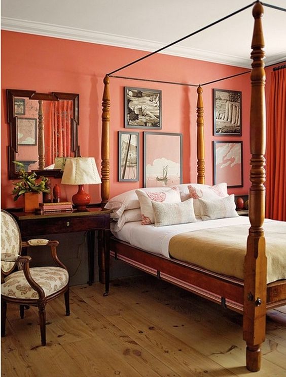 a vintage bedroom with an orange accent wall, a vintage wooden canopy bed, a gallery wall and dark stained furniture is all chic and cool