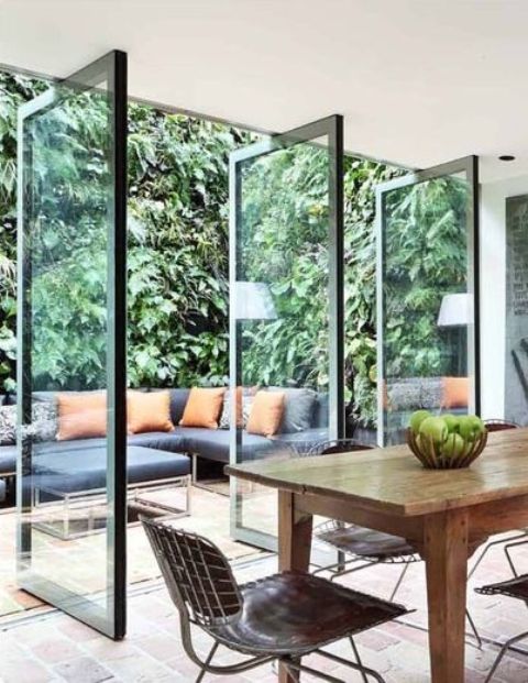 a wall to a pivate terrace done with a series of pivot door is a fantastic idea as it allows to open up the space any time