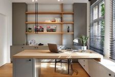 a welcoming contemporary home office with light grey storage units, stained shelves, a built-in matching desk and a black chair