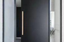 an ultra-minimalist black pivot door with a metallic handle is a fabulous idea for a minimalist home and a very sleek entrance