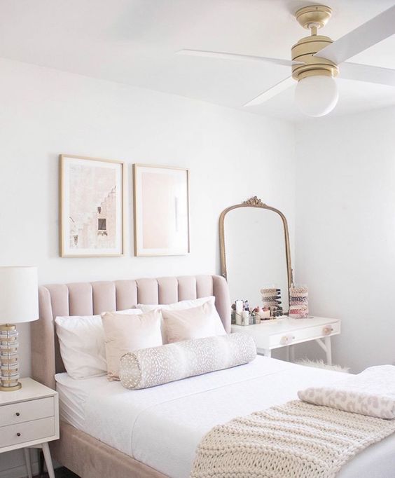 a beautiful neutral bedroom with a blush bed, neutral bedding, a small vanity and a mirror, a white nightstand, a mini gallery wall