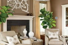 16 a welcoming taupe living room with a vintage-styled fireplace, tan chairs, a woven coffee table, statement potted plants and polka dot pillows