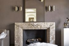 17 an exquisite taupe living room with a non-working fireplace, a refined mirror, metallic sconces, white ottomans and poufs and taupe furniture