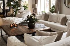 21 a grey living room with creamy sofas and a lounger, taupe and creamy pillows, taupe curtains, a duo of rich-stained coffee tables