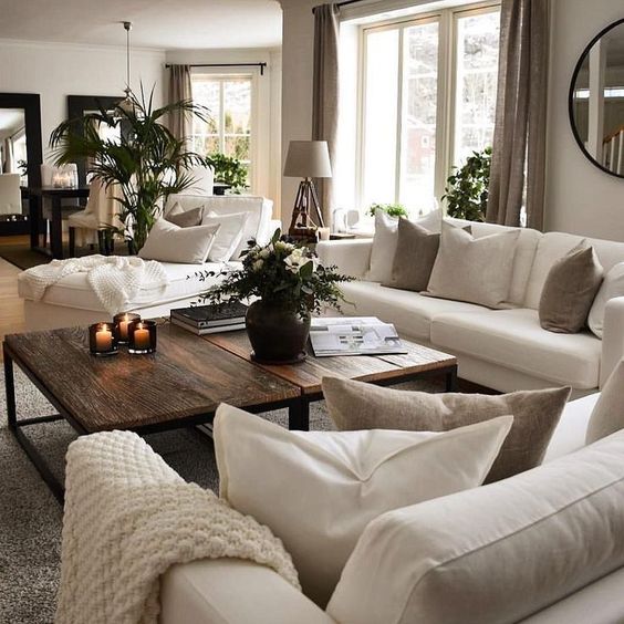 a grey living room with creamy sofas and a lounger, taupe and creamy pillows, taupe curtains, a duo of rich-stained coffee tables