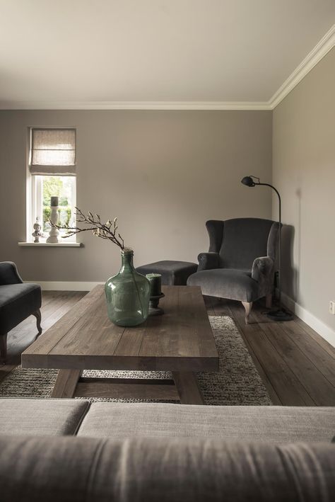 a light grey living room with taupe seating furniture, a low wooden coffee table, candles and a green vase with a branch