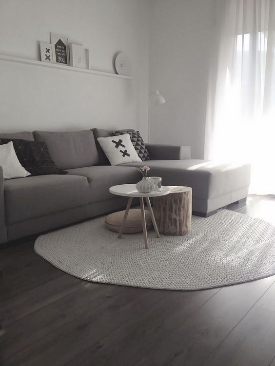 a small minimalist living room with a ledge gallery wall, a taupe sectional, a duo of coffee tables and printed pillows