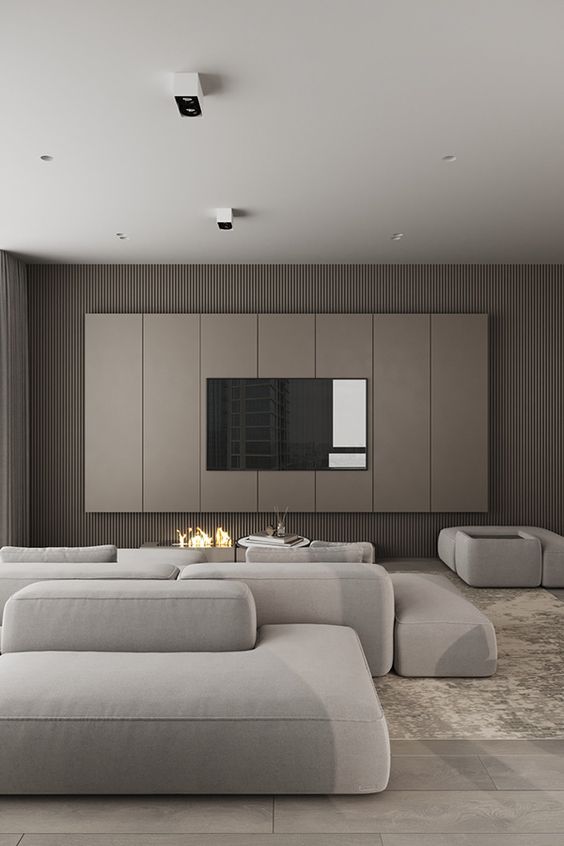 an ultra-minimalist living room with taupe wooden slab walls, a tan paneled accent with a TV, an open fireplace, neutral seating furniture
