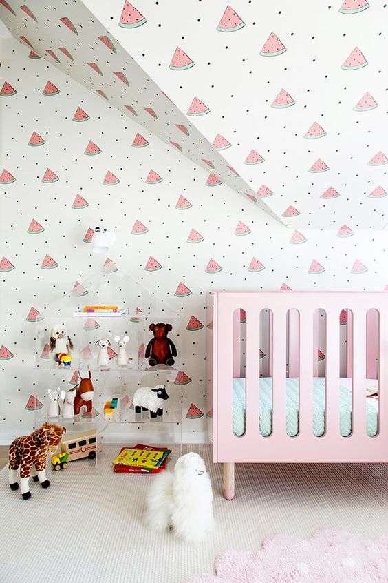 a bright and fun contemporary nursery with a watermelon wallpaper wall, a pink crib, an acrylic shelf with lots of toys is a lovely idea