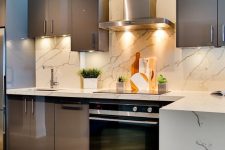 a chic taupe kitchen with glossy cabinets, a white marble tile backsplash and countertops, built-in appliances is a bold idea to try