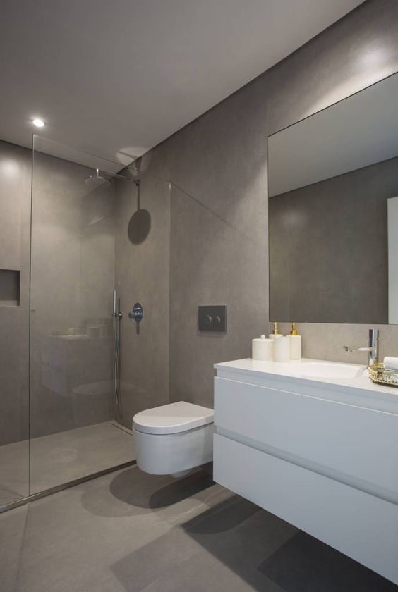 a minimalist taupe bathroom with concrete walls, floor and a shower space, a white floating vanity, a large mirror and white appliances