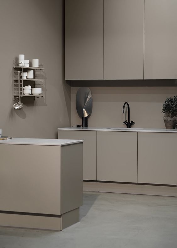 a minimalist taupe kitchen with sleek matte cabinets, a taupe backsplash and white countertops, an open shelf and black fixtures is gorgeous