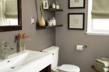 a modern taupe bathroom with a dark stained vanity, a wooden stool and shelves, white appliances, green touches and a mini gallery wall
