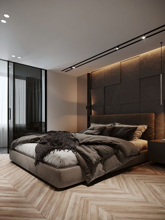 a stylish and refine dmodern bedroom with a taupe accent wall, a taupe upholstered bed with matching bedding, built in lights and glass sliding doors