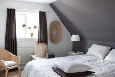 a taupe bedroom with a taupe accent wall, a taupe bed, neutral bedding, black curtains, rattan chair and baskets