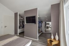 a taupe bedroom with a taupe bed, white and taupe bedding, creay curtains and a walk-in closet integrated right here