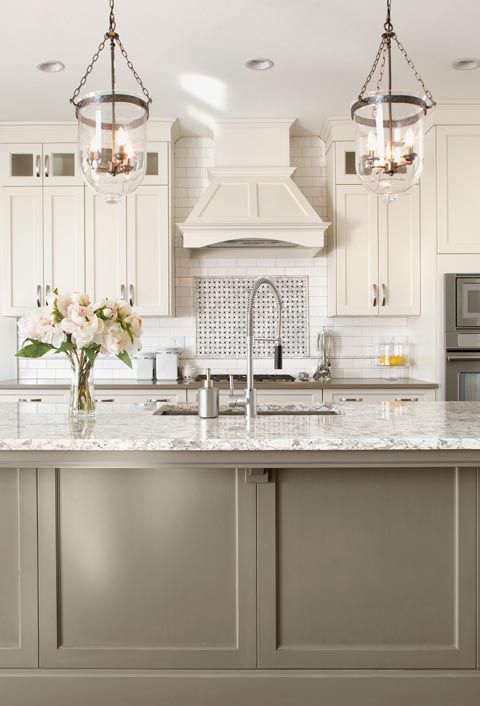 a white vintage kitchen with shaker cabinets, a white tile backsplash and white countertops, a taupe kitchen island with a white countertop