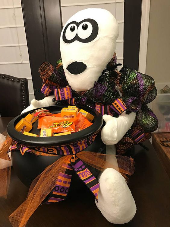 a mummy holding a witch's cauldron with sweets and candies is a great idea for styling your porch at Halloween