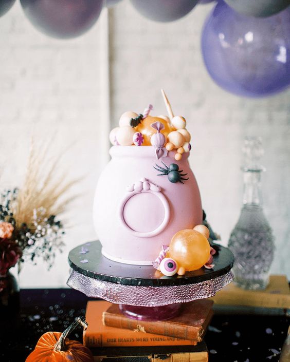 a pink cauldron with candies and sweets in pastel colors is a great way to serve some food in a truly Halloween way
