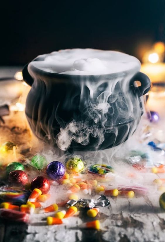 a lovely Halloween decoration of a black cauldron with smoke and lots of sweets around is easy to make and looks cool