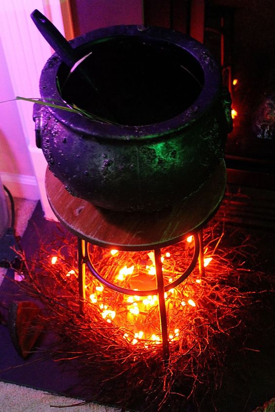 a lovely Halloween decoration of a wooden table with lights that imitate fire, and a culdron on top is a cool idea for indoor decor