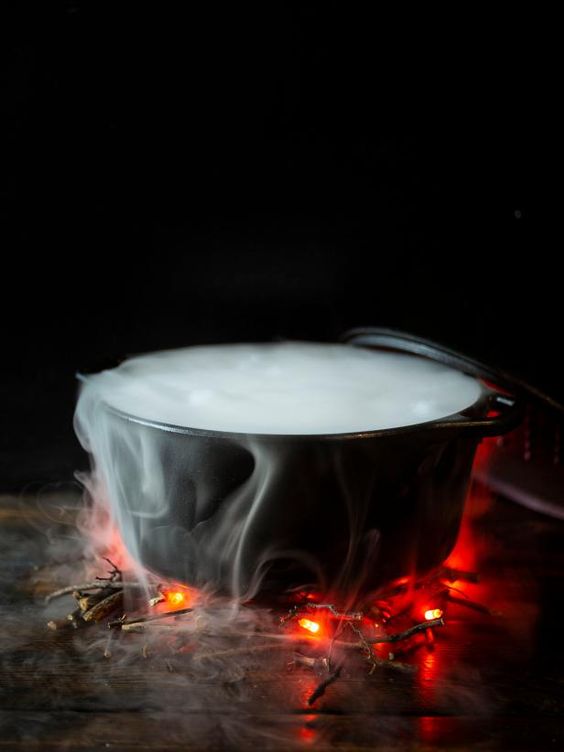 a simple and modern Halloween decoration of a cauldron with smoke and branches and lights that imitate fire is cool