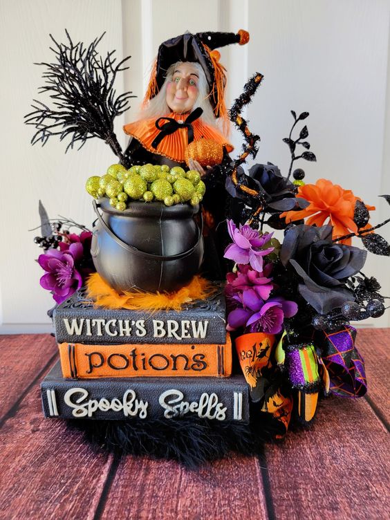 a whimsy Halloween decoration of vintage books, bold and dark blooms and leaves, a witch, a cauldron and some more stuff