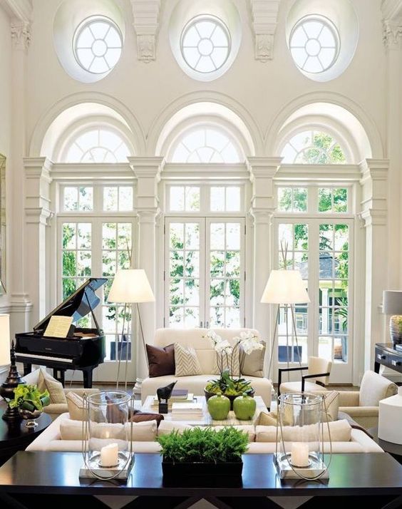 a beautiful living room with neutrals and dark touches, with double height French windows and round ones, with lots of greenery