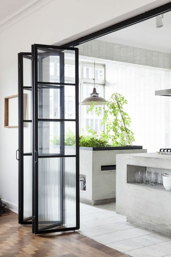 a black frame and frosted glass folding door is a pretty solution for a contemporary space and it echoes with a black countertop in the kitchen