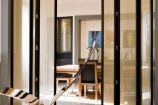 a black frame folding door with delicate light curtains attached is a lovely divider for spaces and it gives a bit more privacy to the rooms