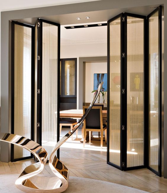 a black frame folding door with delicate light curtains attached is a lovely divider for spaces and it gives a bit more privacy to the rooms