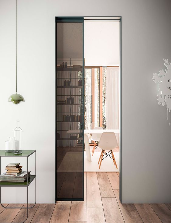 a black glass and green frame pocket door is a very cool and bold solution to separate the spaces and add color