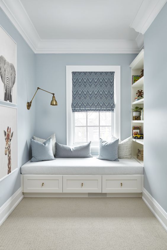 a coastal windowsill reading nook with an upholstered bench, drawers and bookshelves on one side of it