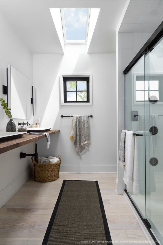 a contemporary black and white bathroom accented with a small French window and a large skylight is a fab space