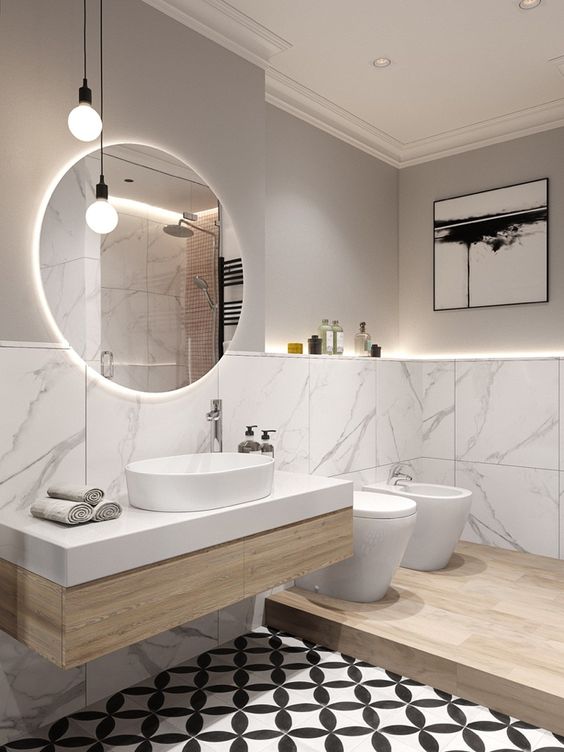 a contemporary greige bathroom clad with white marble tiles, a floating vanity, white appliances and neutral chromatic fixtures, pendant bulbs